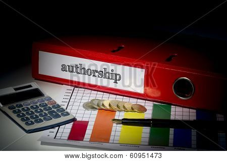 The word authorship on red business binder on a desk