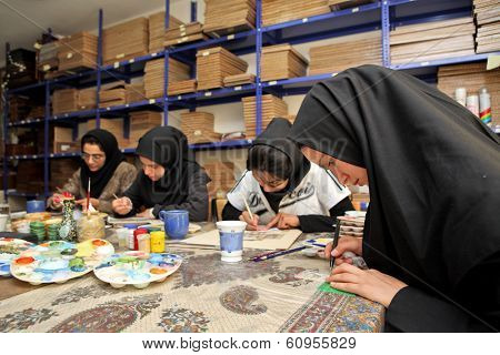 ESFAHAN, IRAN - DECEMBER 01, 2007:  Muslim women artists in black headscarfs paint traditional Persian miniature