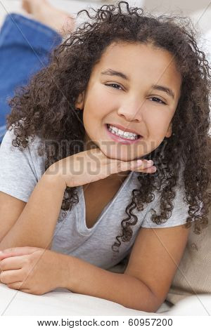 Beautiful young mixed race interracial African American girl child laying down smiling and showing off her perfect white teeth