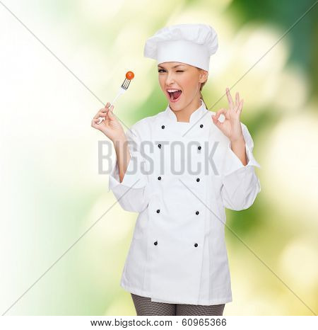cooking and food concept - smiling female chef, cook or baker with fork and tomato showing ok sign