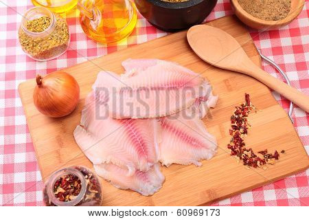 Raw fish tilapia on cutting board and spices