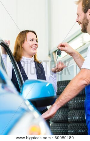 Female client and mechanic in auto workshop or MOT with car for service inspection