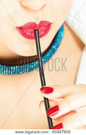 close up of woman drinking cocktail through straw
