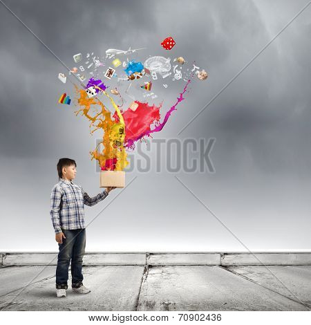 Young boy splashing colorful paint from bucket
