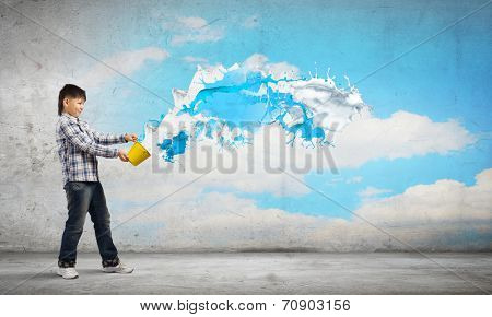 Young boy splashing colorful paint from bucket