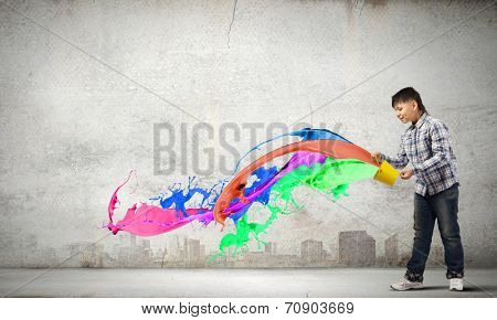 Young boy splashing colorful paint from bucket