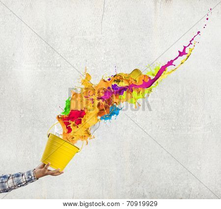 Close up of hand splashing colorful paint from bucket