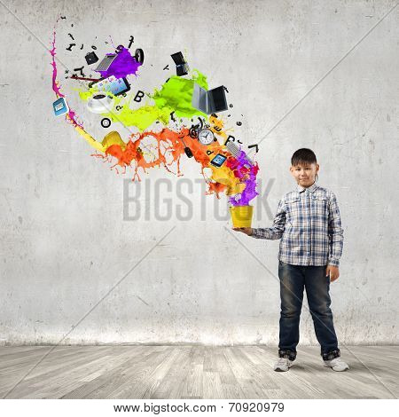 Young boy splashing colorful paint from bucket