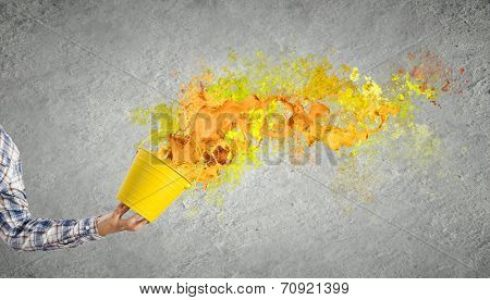 Close up of hand splashing colorful paint from bucket