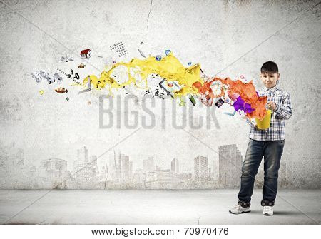 Young boy splashing colorful paint from bucket