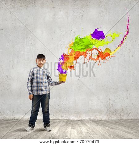 Young boy splashing colorful paint from bucket