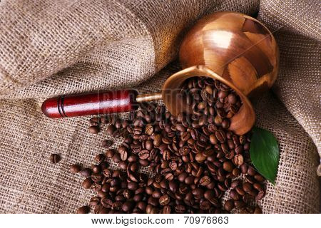Coffee beans in ibrik on sacking background closeup