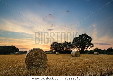 Rural Landscape Image Of Summer Sunset Over Field Of Hay Bales