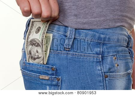 the hand of a young woman pulling a dollar money bill out of pocket of her jeans