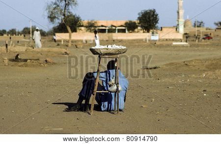 Man Sells Sweets And Protects Herself From The Midday Heat By Sitting In The Shadow Of The Basket