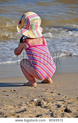 menina, sentando-se na costa e observando as ondas