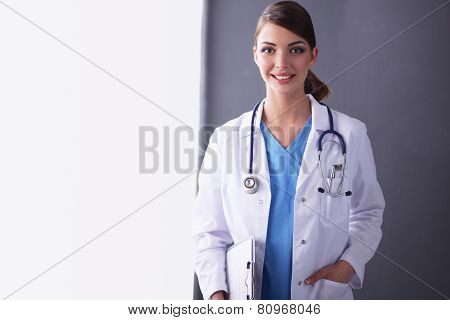 Young doctor or medic with clipboard and stethoscope isolated on grey background