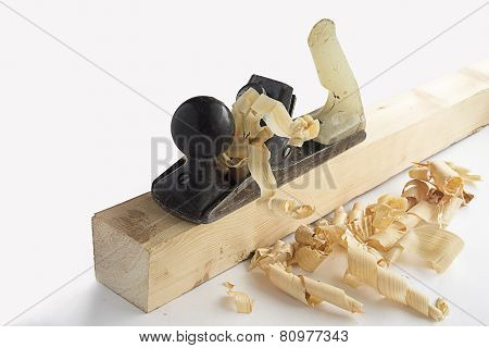 Old iron planer on a wooden bar with chips on white background