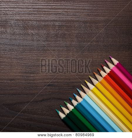 colorful pencils over brown table background