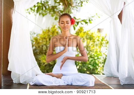 
Young woman practicing yoga in Buda pose in nature under baldachin