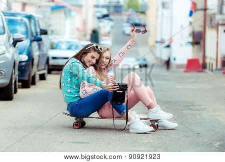 Hipster girlfriends taking a selfie in urban city context - Concept of friendship and fun with new t