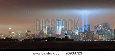 New York City Manhattan downtown skyline panorama at night with statue of liberty and light beams in memory of September 11 viewed from New Jersey waterfront.