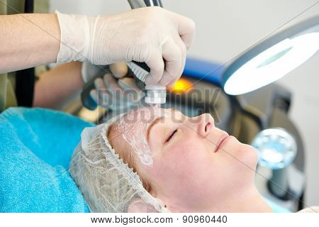 Young woman under laser therapy cosmetology procedure 