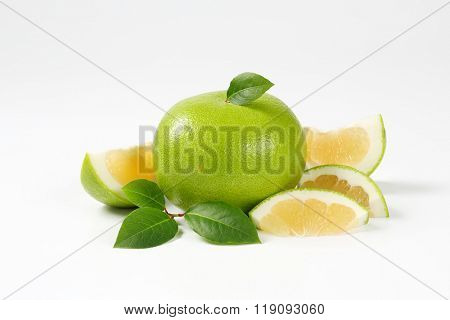 whole and sliced green grapefruit on white background