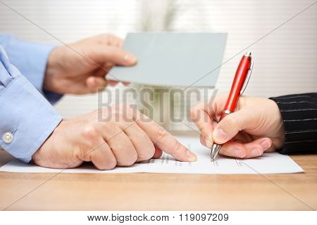 employer shows employee where to sign and giving her booklet at the same time