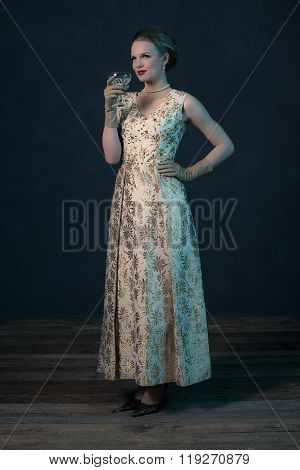 Chique Vintage 50S Fashion Woman In Gold Dress Holding Champagne Glass.