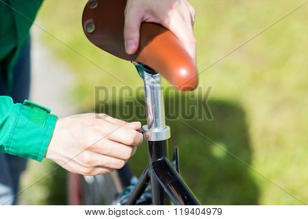 people, vehicle, eisure and lifestyle - close up of man adjusting fixed gear bike saddle high