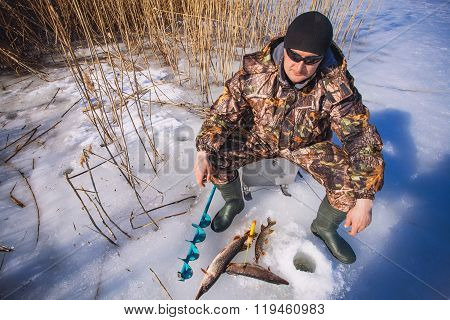 ice fisherman with pike caught on a tip up