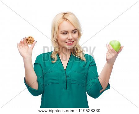 healthy eating, junk food, diet and choice people concept - smiling woman choosing between apple and cookie