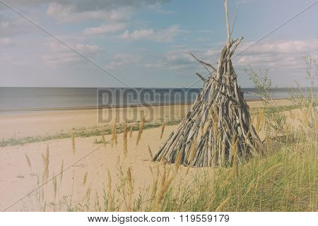 Shelter from wooden branches on a sandy beach in the grass on the Baltic Sea