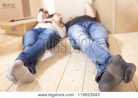 young couple relaxing after moving on wooden floor