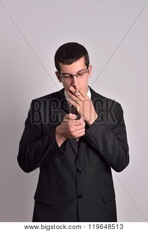 Young Man Dressed In Tuxedo Lighting Cigarette In Studio