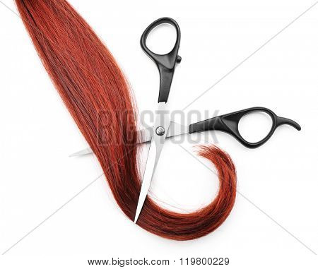 Hairdresser's scissors with strand of red hair, isolated on white