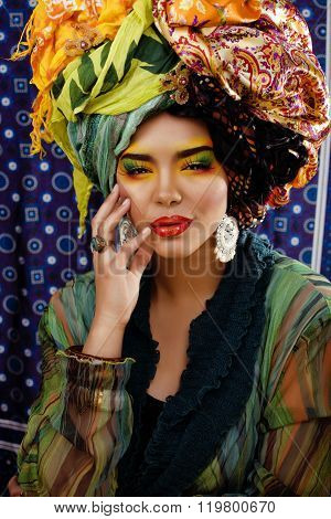 beauty bright woman with creative make up, many shawls on head like cubian, ethno look closeup