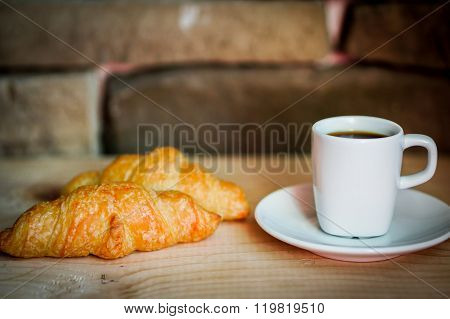 Black Croissants With Black Coffee On Wooden Background