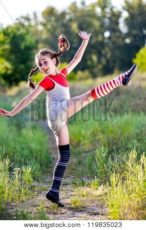 A funny cute outdoor portrait of a little girl presenting Pippi Longstocking and showing out out her tongue.