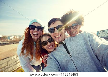 tourism, travel, people, leisure and technology concept - group of smiling teenage friends taking selfie on city street