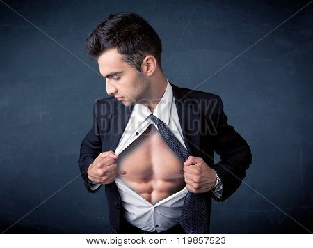 Businessman tearing off his shirt and showing mucular body concept on background