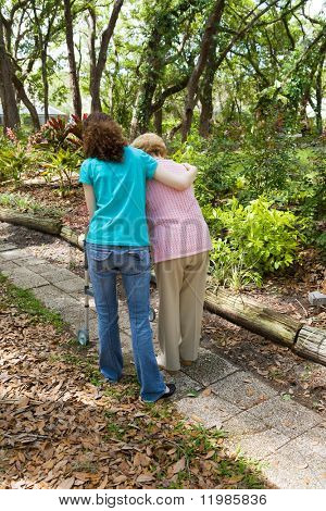 Tiener meisje helpen senior vrouw Maak een wandeling door het park.  Verticale weergave met ruimte voor tekst.