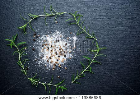 Salt, pepper and rosemary on a chopping board