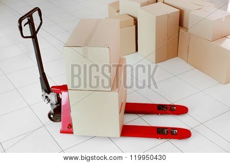 Fork pallet truck with stack of cardboard boxes indoors