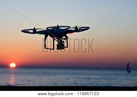Flying drone with camera on the sky at sunset