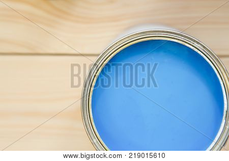 Painting an appartment. A tin can of blue oil paint on a light uncolored wooden background. Close up. Top view. Space for your text or pruduct display.