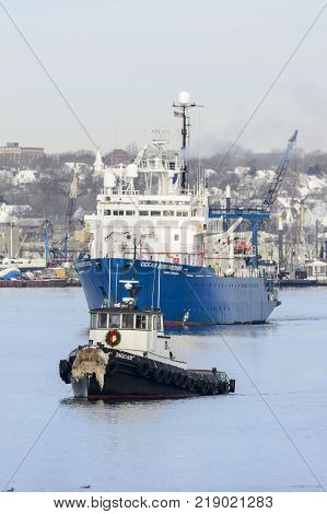 New Bedford Massachusetts USA - December 15 2017: Tug Jaguar and research vessel Ocean Researcher on Acushnet River with New Bedford backdrop (vertical format)