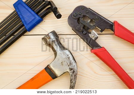 Renovating a house. A set of repair tools- hex keys, a hammer and pilers on a light uncolored wooden background. Close up. Top view. Space for your text or pruduct display.