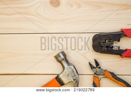 Repairing and construction concept. A set of repair tools- a hammer and pilers on a light uncolored wooden background. Top view. Space for your text or pruduct display.
